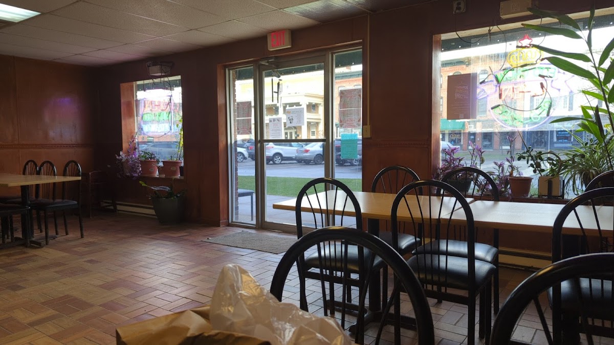 Foo Chow Restaurant dining room with wood tables, black chairs, plants, and warm brown walls
